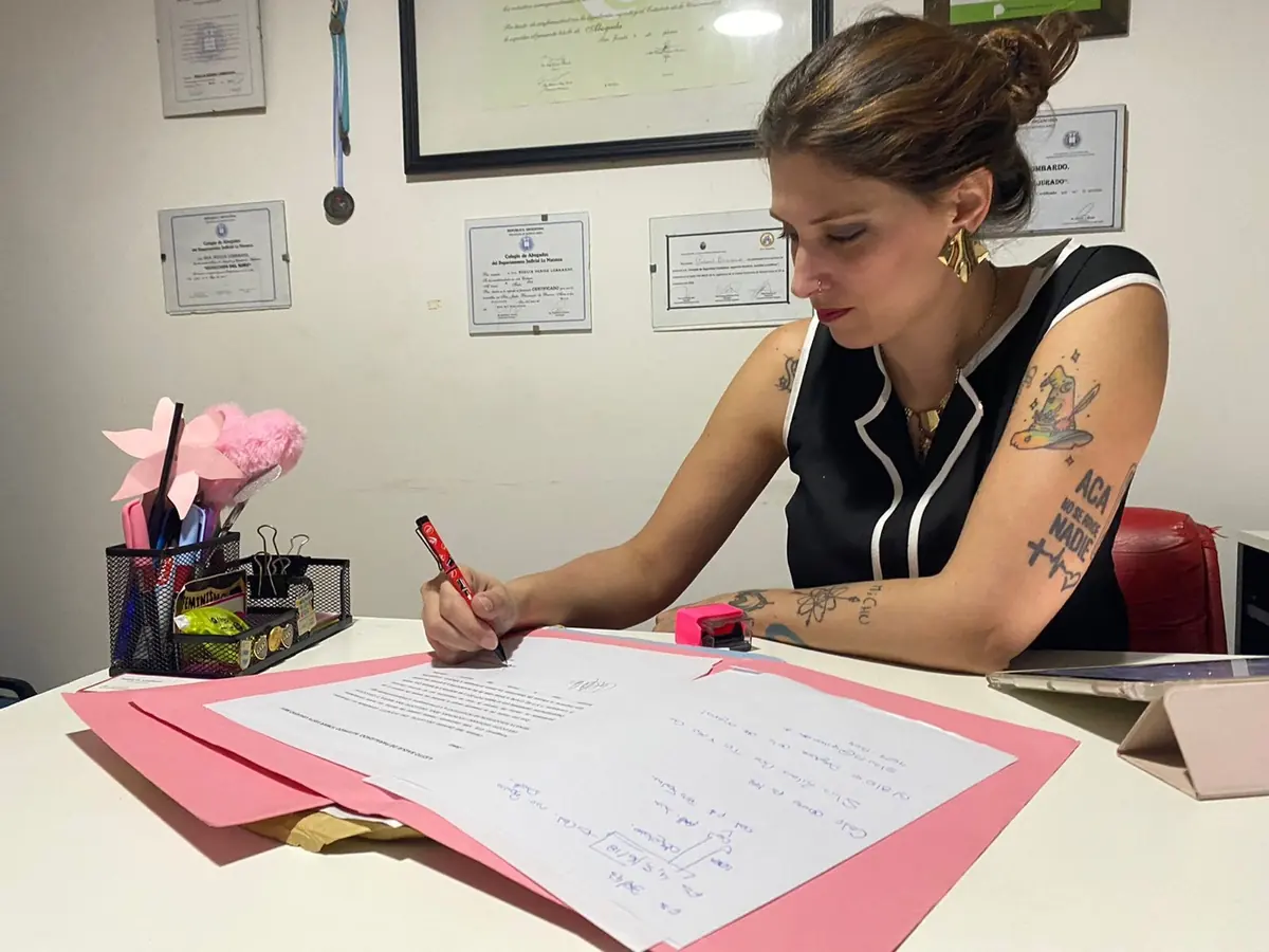 Noelia D. Lombardo firmando documentos en su escritorio